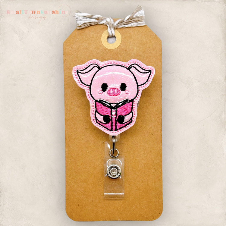 pig hugging book badge reel
