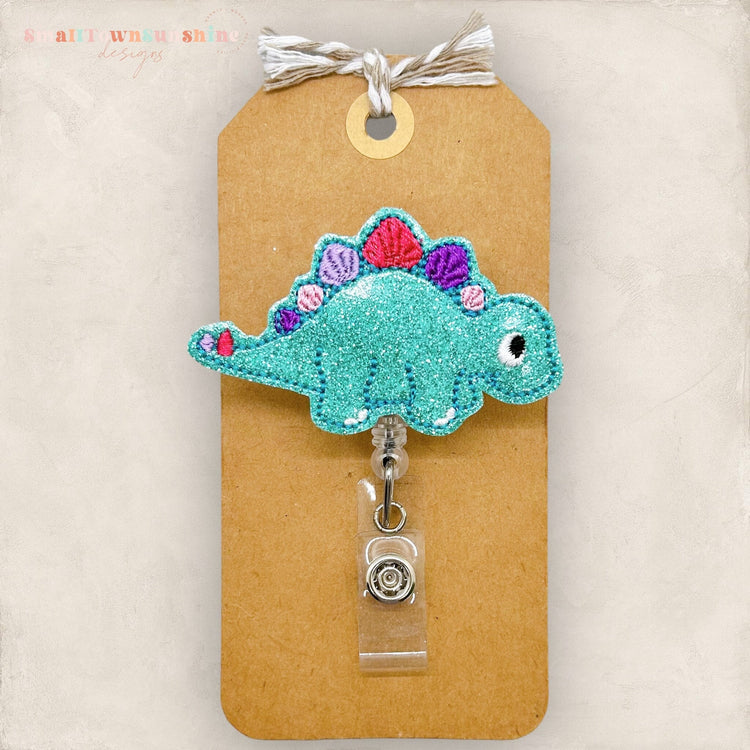 blue stegosaurus with pastel rainbow spikes badge reel