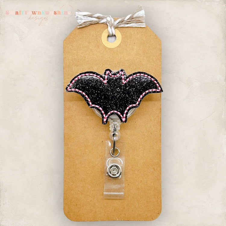 glittery black bat with pink edges badge reel