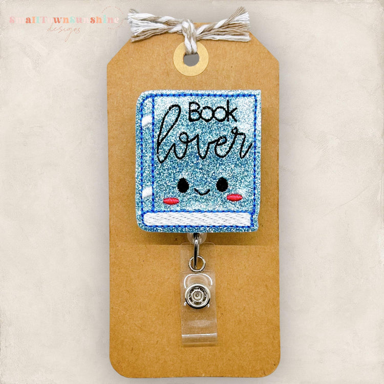 blue glitter book with cute face and book lover embroidered on the front