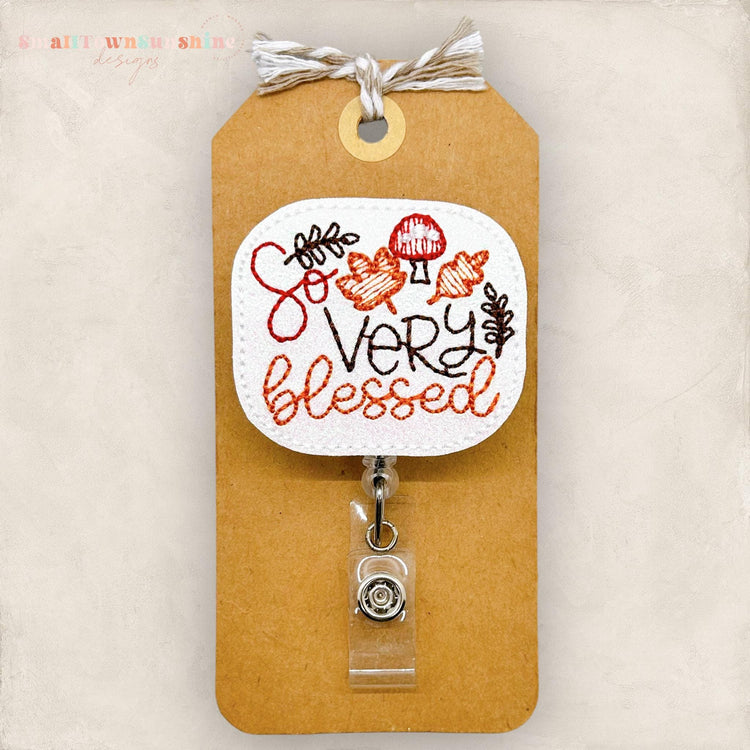 mushrooms and leaves embroidered with the words so very blessed for a badge reel cover