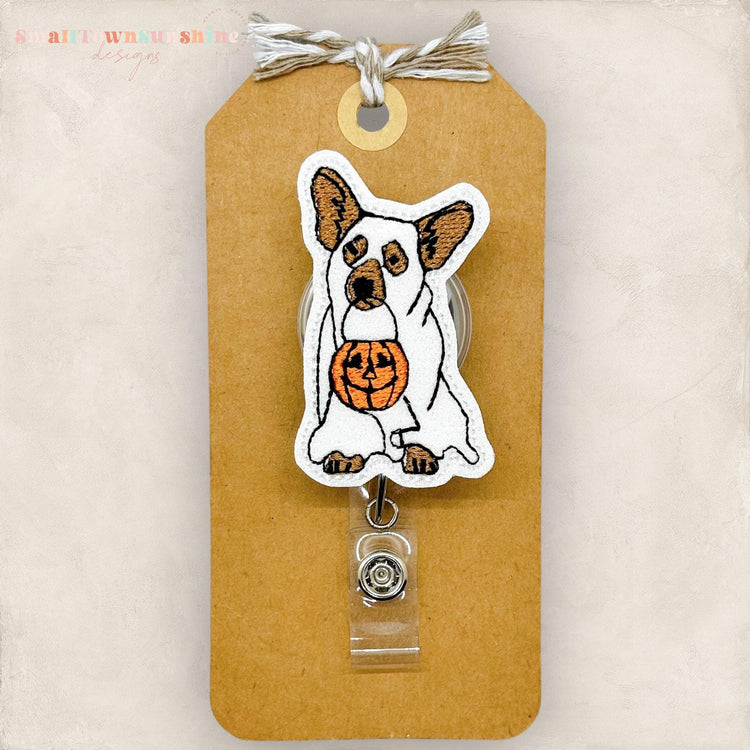 cute dog dressed as a ghost holding trick or treat pumpkin badge reel topper