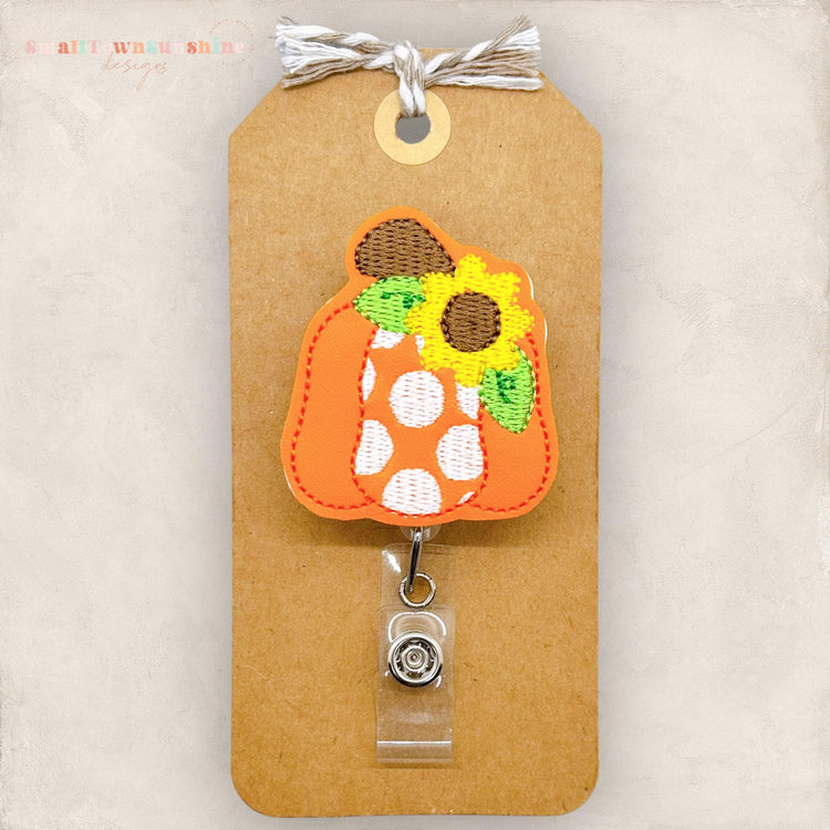 badge reel with a cute orange pumpkin donned with white polka dots and a sunflower