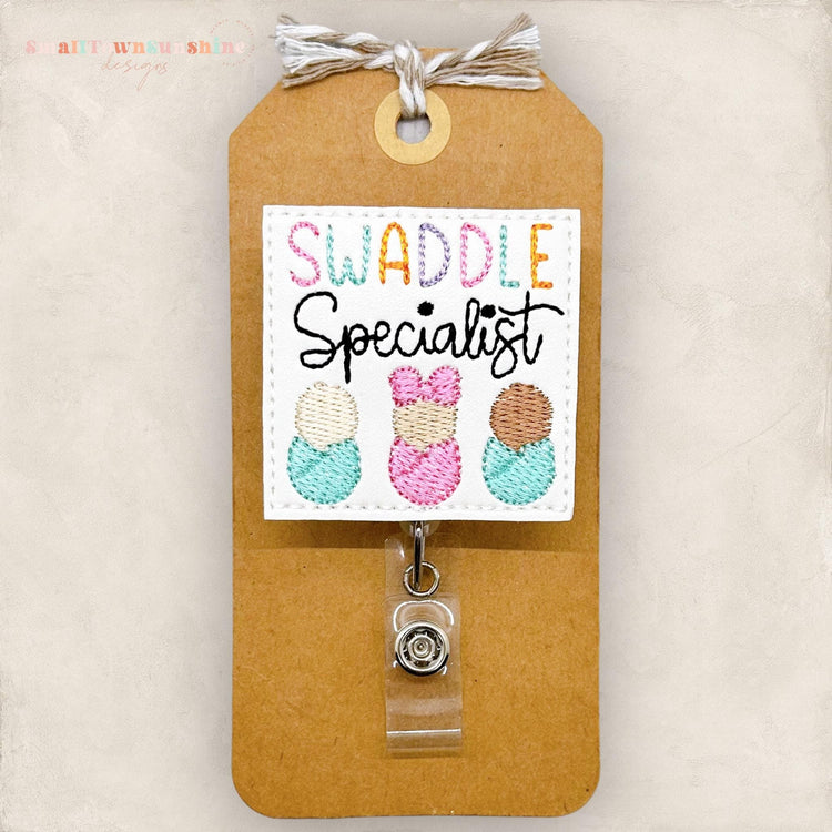 swaddle specialist badge reel topper with three diverse embroidered babies