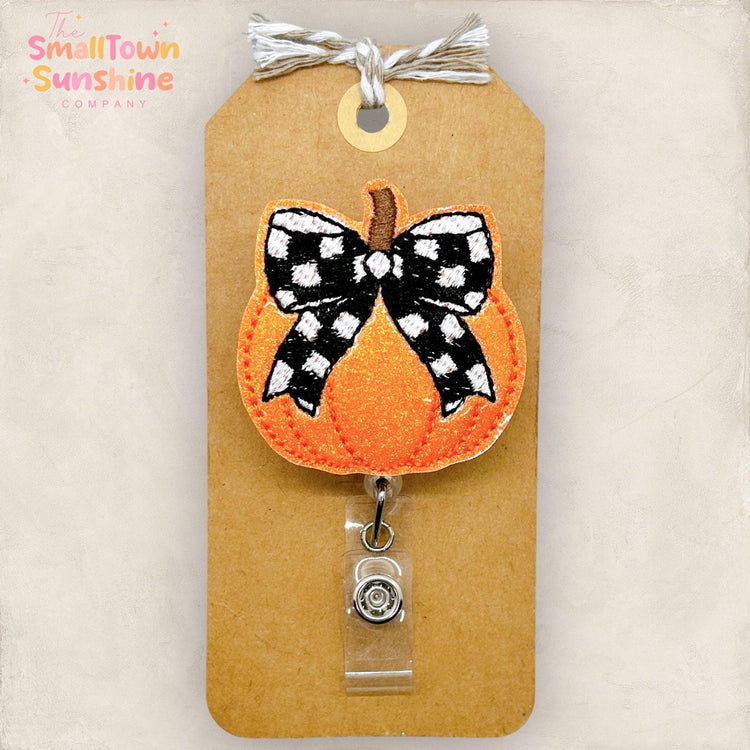orange pumpkin with black and white bow embroidered badge reel topper