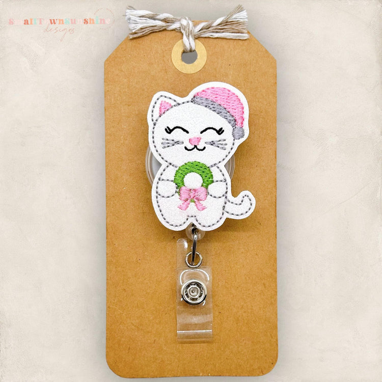 white cat with pink santa hat and wreath embroidered badge reel topper
