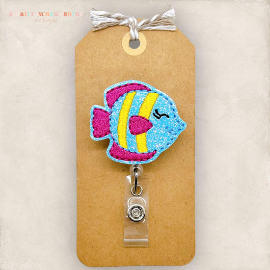 A colorful, hand-sewn fish-shaped badge or lanyard with a clear plastic tag attached to it.