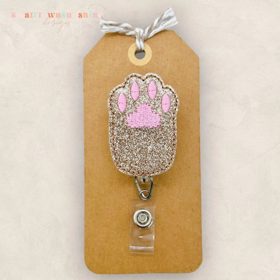 A brown paper tag with a glittery paw print charm attached to it.