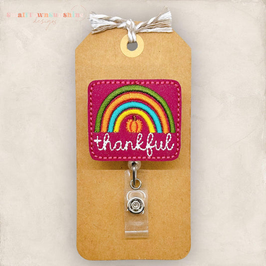 fall colored rainbow with a pumpkin and the word thankful embroidered on maroon vinyl for a badge reel