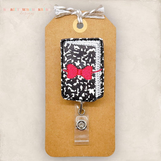 composition notebook with pink bow badge reel