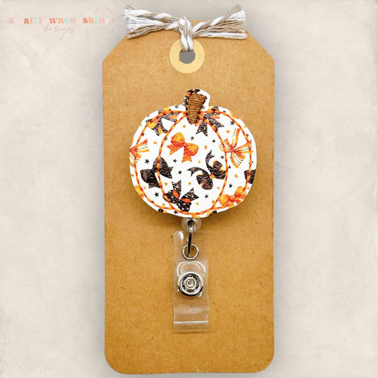 embroidered pumpkin with a orange and black coquette bow print, badge reel topper