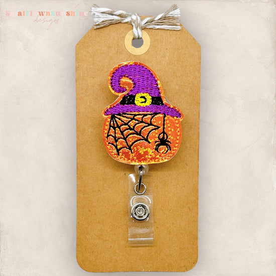 pumpkin with spider and spiderweb with a purple witch hat embroidered badge topper