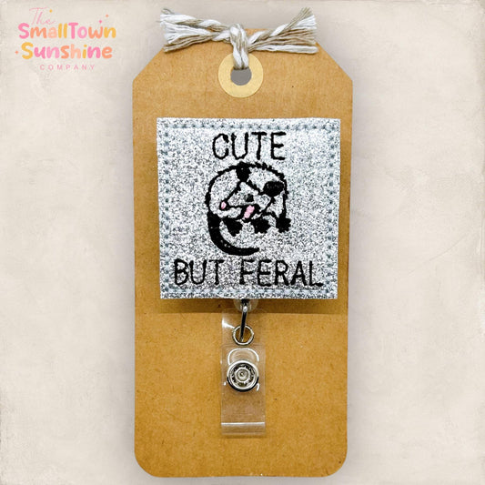 glittery cute but feral embroidered badge reel topper