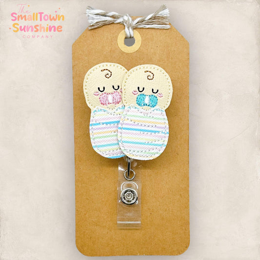 two embroidered babies with striped hospital blankets and pink and blue pacifiers