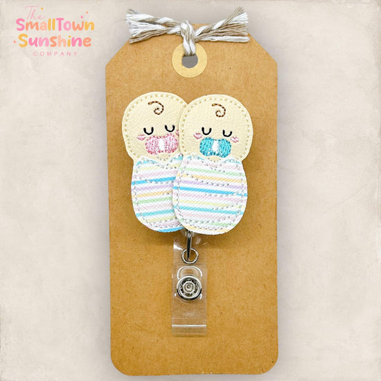 two embroidered babies with striped hospital blankets and pink and blue pacifiers