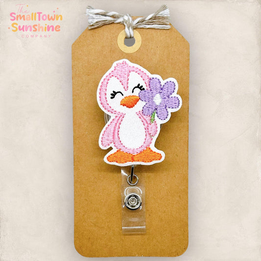 embroidered pink penguin with purple daisy badge reel topper